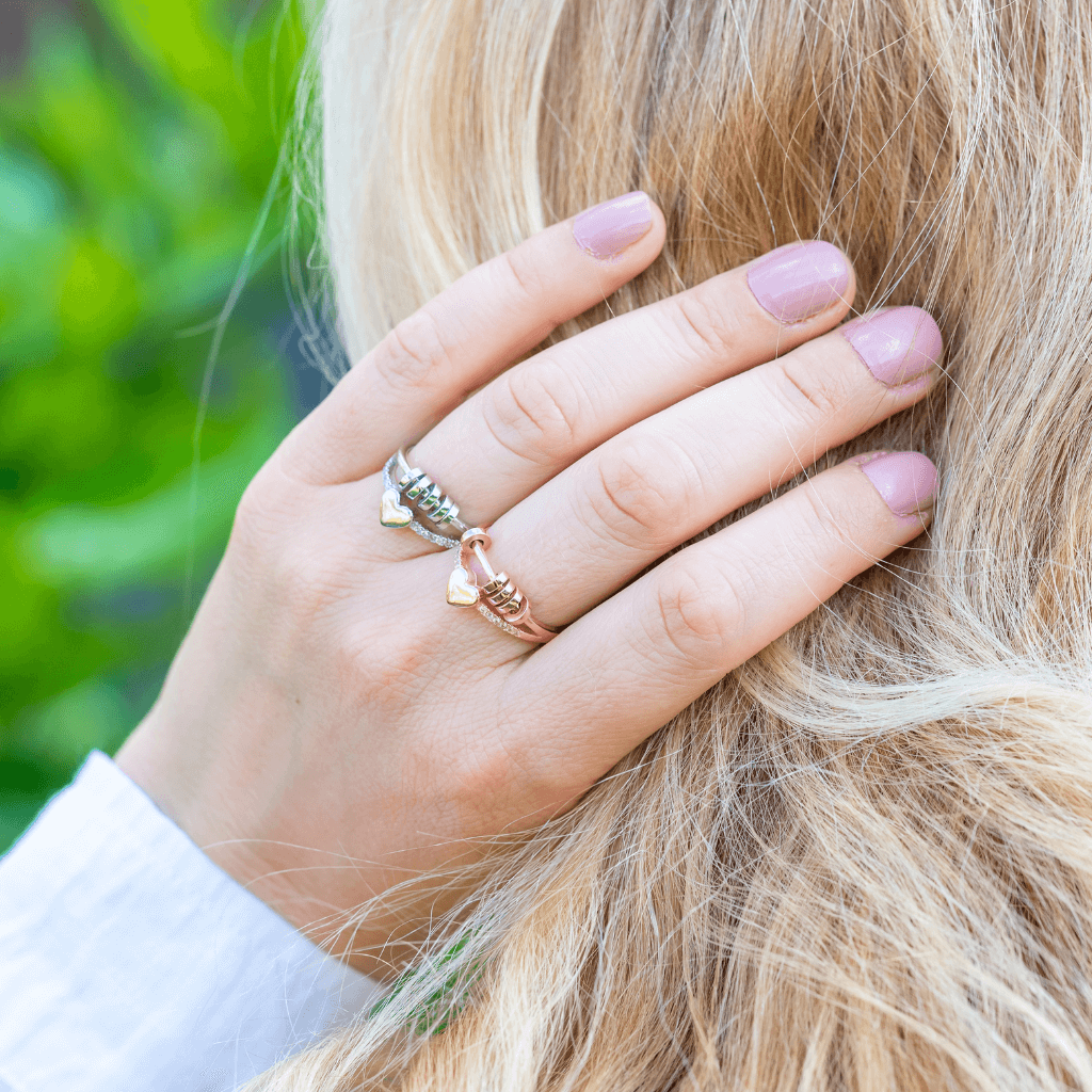 Two fidgeting rings with heart and beads on a grey background